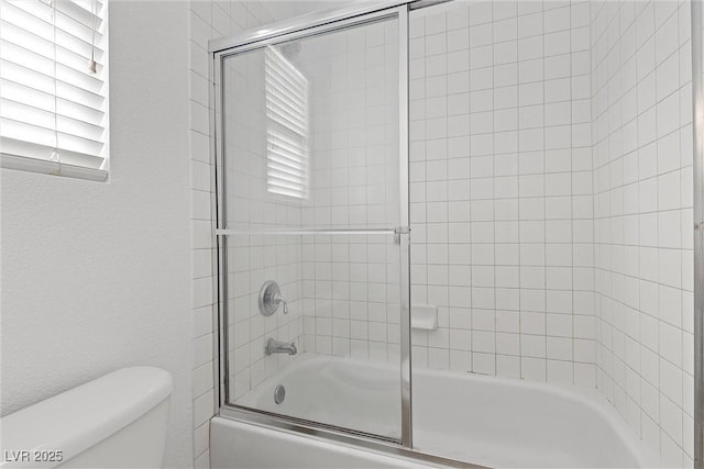 bathroom with shower / bath combination with glass door and toilet