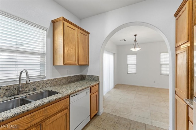 kitchen featuring stone counters, white dishwasher, hanging light fixtures, sink, and light tile patterned flooring