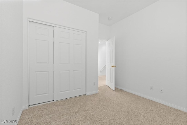 unfurnished bedroom with light colored carpet and a closet