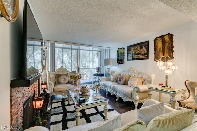 living room featuring a tile fireplace, hardwood / wood-style floors, a textured ceiling, and a wall of windows