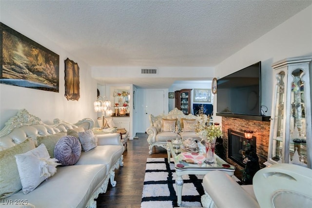 living room with dark wood-type flooring, a textured ceiling, and a brick fireplace