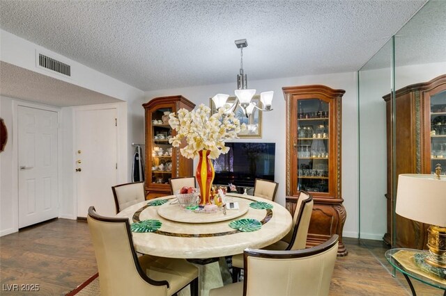 dining space featuring a chandelier, a textured ceiling, and dark hardwood / wood-style flooring