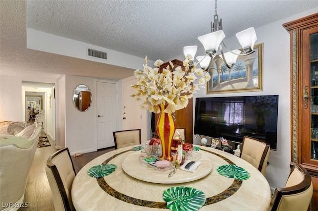 dining room featuring hardwood / wood-style flooring, an inviting chandelier, and a textured ceiling