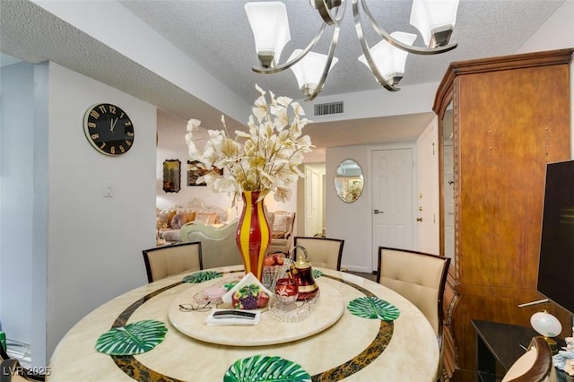 dining area with a textured ceiling and a notable chandelier