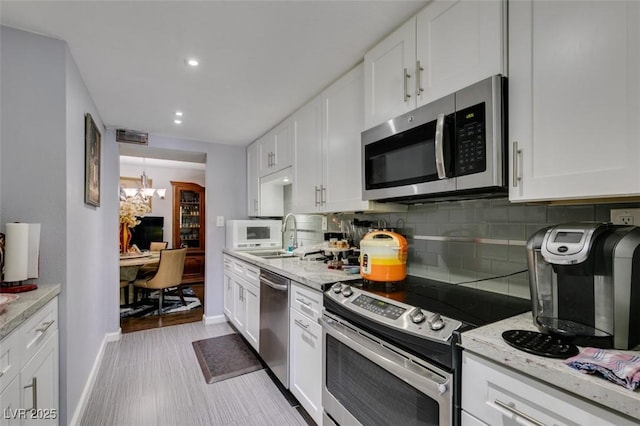 kitchen with stainless steel appliances, white cabinetry, and decorative backsplash