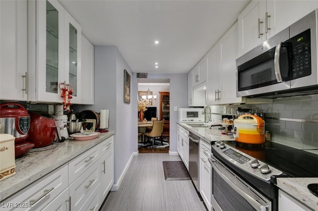 kitchen featuring a chandelier, white cabinetry, backsplash, stainless steel appliances, and light stone counters