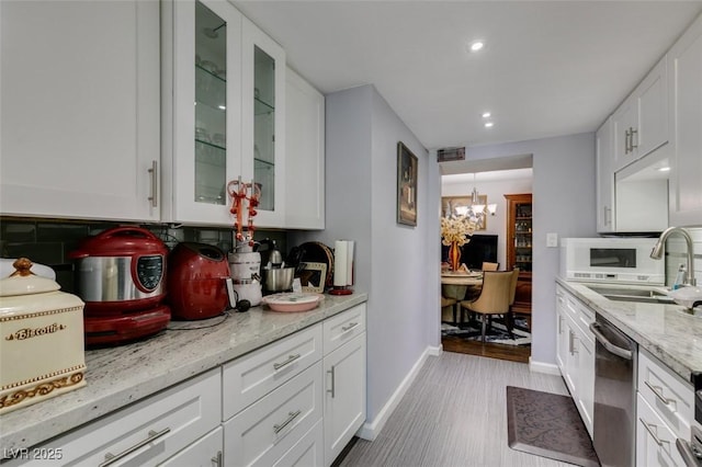 kitchen featuring sink, stainless steel dishwasher, white cabinetry, and light stone counters