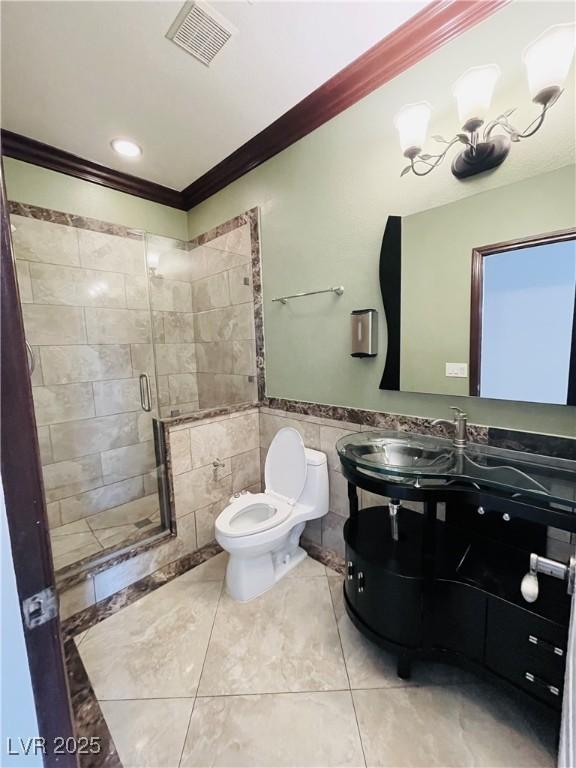 bathroom with an enclosed shower, vanity, tile walls, toilet, and crown molding