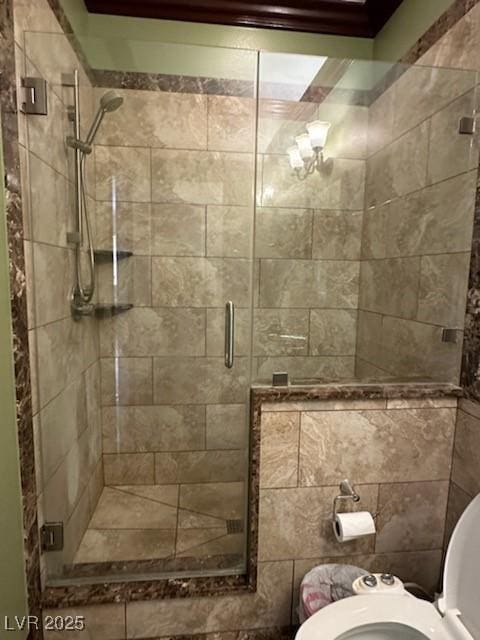 bathroom featuring toilet and a shower with shower door