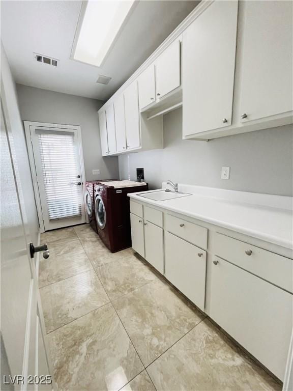 clothes washing area featuring cabinets, sink, and washing machine and clothes dryer