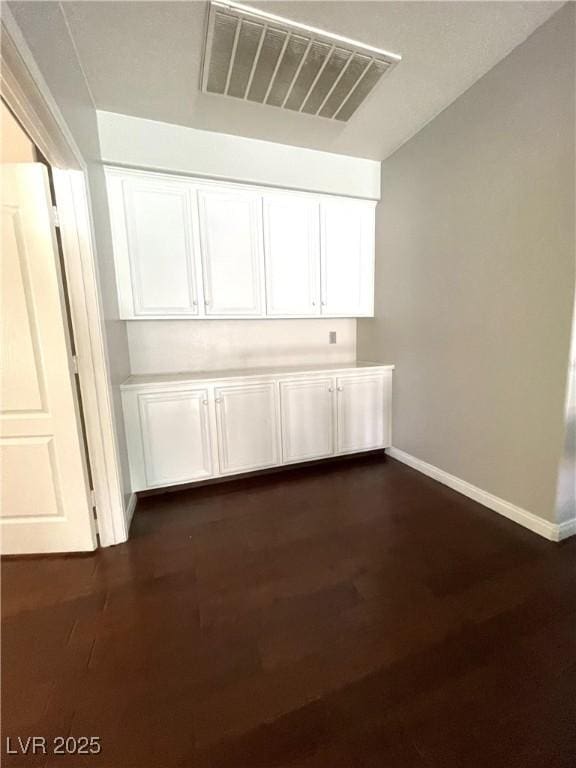 interior space with dark wood-type flooring and white cabinets