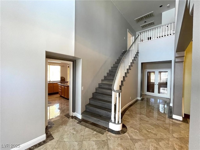 staircase with a high ceiling and french doors