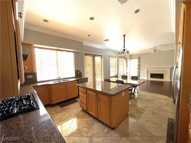 kitchen featuring pendant lighting, black gas cooktop, a healthy amount of sunlight, a center island, and dark stone countertops