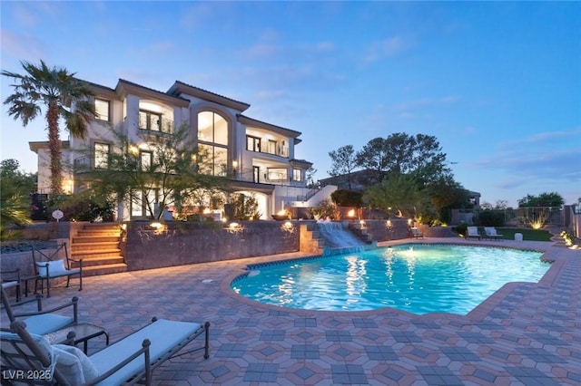 pool at dusk featuring a patio area and pool water feature