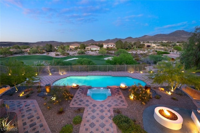 pool at dusk with a mountain view, a patio area, and a fire pit