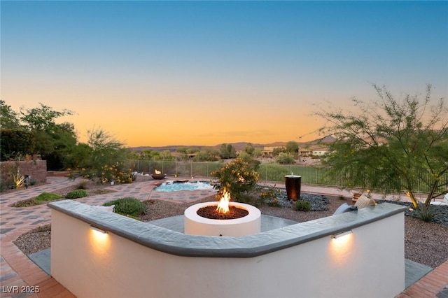 patio terrace at dusk featuring a fire pit and a mountain view