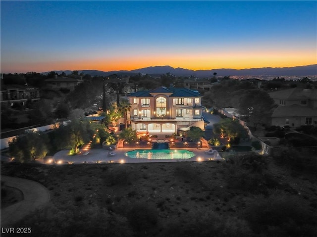 back house at dusk with a mountain view and a patio