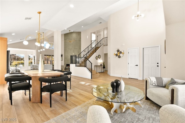 living room featuring light hardwood / wood-style floors, high vaulted ceiling, and an inviting chandelier