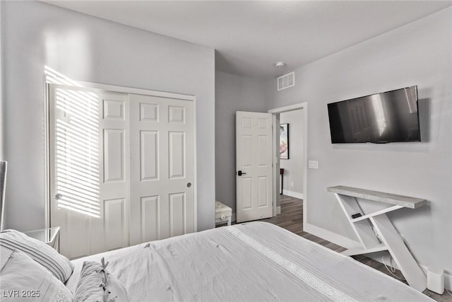 bedroom with dark wood-type flooring and a closet