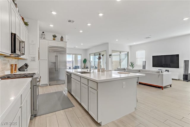 kitchen featuring white cabinets, sink, light hardwood / wood-style flooring, an island with sink, and high quality appliances