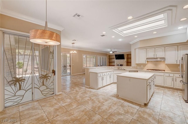 kitchen featuring kitchen peninsula, ornamental molding, decorative light fixtures, and a kitchen island