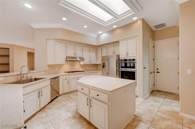 kitchen with crown molding, appliances with stainless steel finishes, sink, a skylight, and a kitchen island