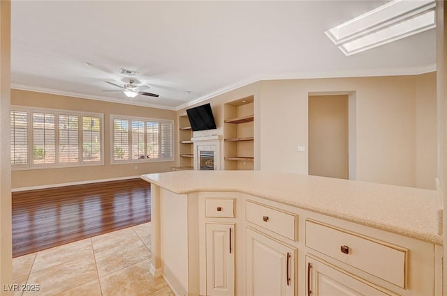 kitchen with built in shelves, light tile patterned flooring, cream cabinets, and crown molding