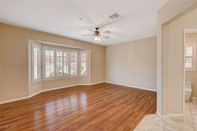 empty room with light wood-type flooring, ceiling fan, and plenty of natural light