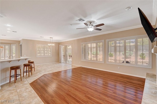 tiled living room featuring ceiling fan with notable chandelier and ornamental molding