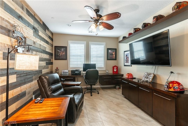 office space featuring ceiling fan and wood walls