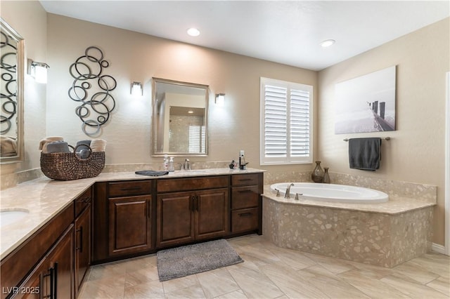 bathroom with tiled tub and vanity