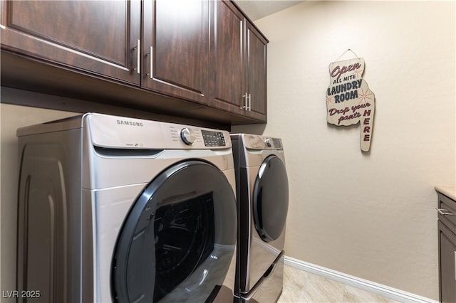 clothes washing area featuring cabinets and separate washer and dryer