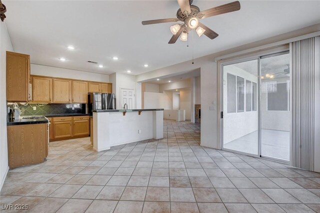 kitchen with a kitchen island, backsplash, refrigerator, and light tile patterned floors