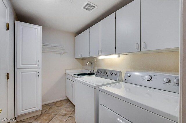 washroom with sink, light tile patterned floors, separate washer and dryer, and cabinets