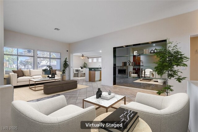 living room with a fireplace, light tile patterned floors, and ceiling fan