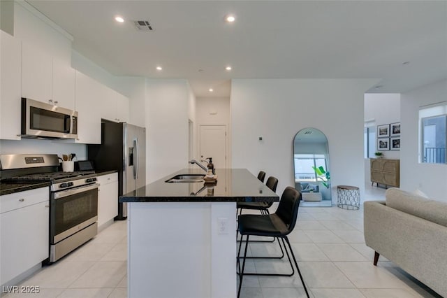 kitchen with sink, white cabinetry, light tile patterned floors, an island with sink, and stainless steel appliances