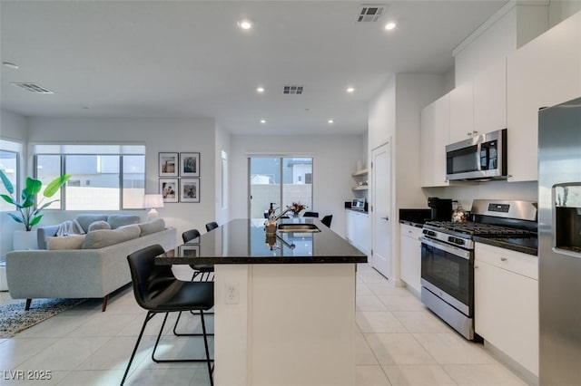 kitchen with sink, white cabinets, appliances with stainless steel finishes, and a kitchen island with sink