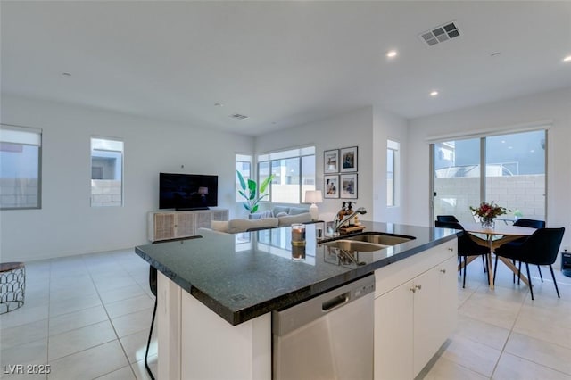 kitchen with white cabinetry, light tile patterned floors, stainless steel dishwasher, sink, and an island with sink