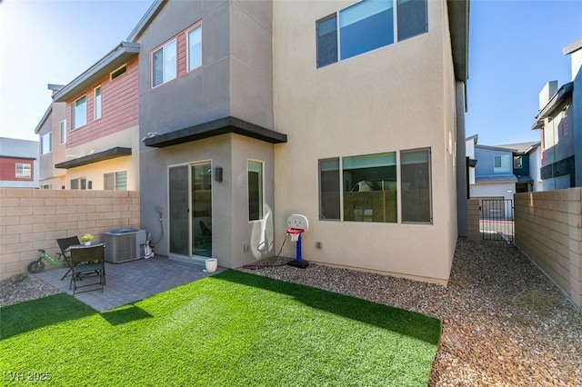 back of property with a lawn, a patio area, and central AC