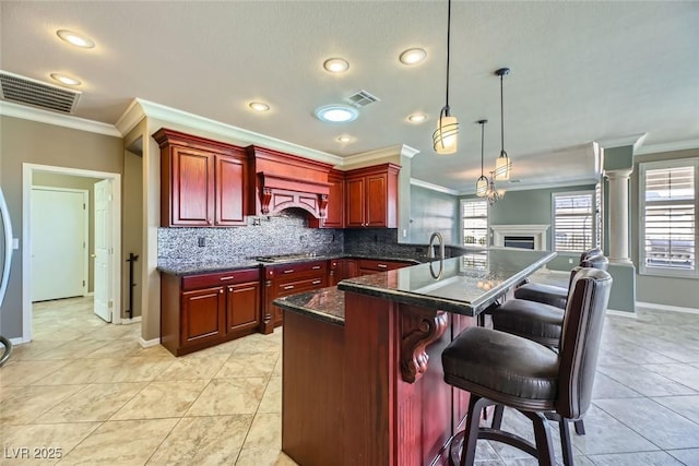 kitchen with a kitchen breakfast bar, stainless steel gas stovetop, hanging light fixtures, light tile patterned flooring, and ornamental molding