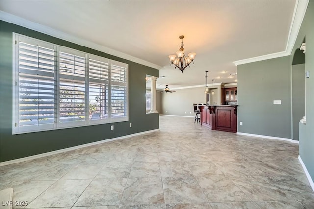 unfurnished dining area featuring decorative columns, crown molding, and ceiling fan with notable chandelier