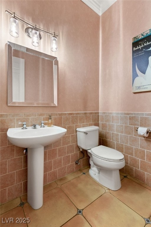 bathroom featuring ornamental molding, toilet, tile patterned flooring, and tile walls