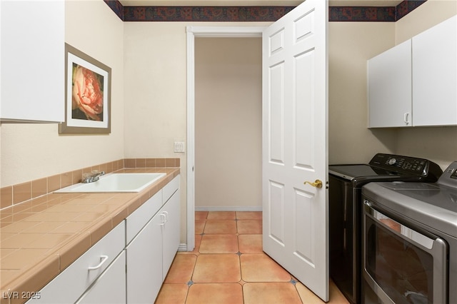 laundry room featuring cabinets, sink, light tile patterned floors, and washer and dryer