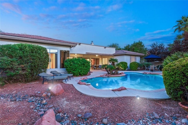 pool at dusk featuring a patio area