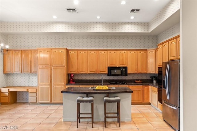 kitchen with a kitchen bar, light tile patterned floors, black appliances, and an island with sink