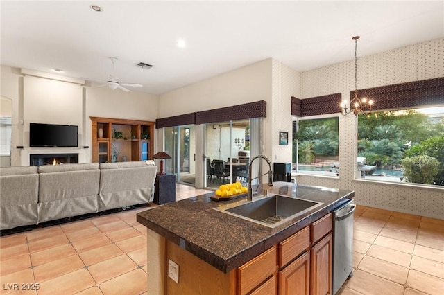 kitchen with ceiling fan with notable chandelier, dishwasher, sink, hanging light fixtures, and a center island with sink