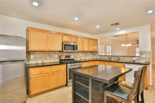 kitchen featuring appliances with stainless steel finishes, decorative backsplash, sink, decorative light fixtures, and a breakfast bar