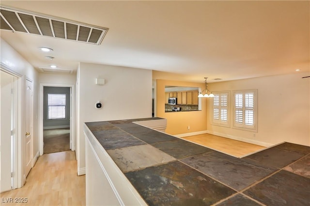 kitchen with decorative light fixtures, a healthy amount of sunlight, light hardwood / wood-style floors, and light brown cabinets