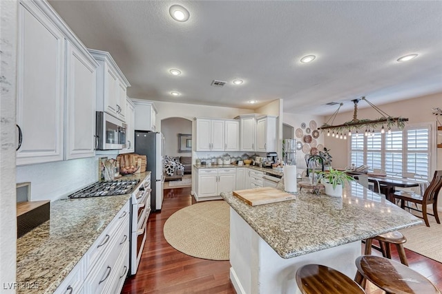 kitchen with light stone countertops, a breakfast bar area, stainless steel appliances, and white cabinets