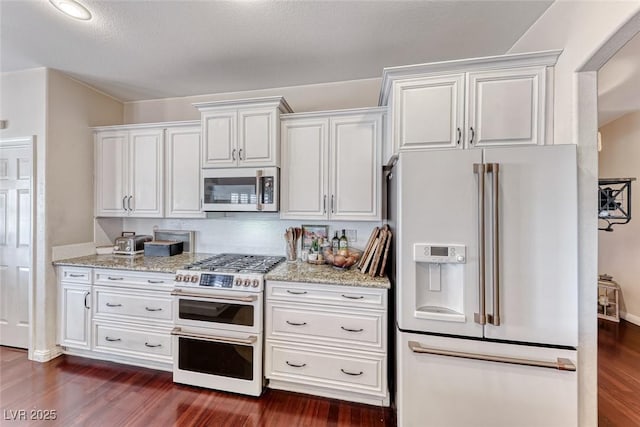 kitchen with white cabinetry, light stone counters, dark hardwood / wood-style flooring, high end white fridge, and range with two ovens